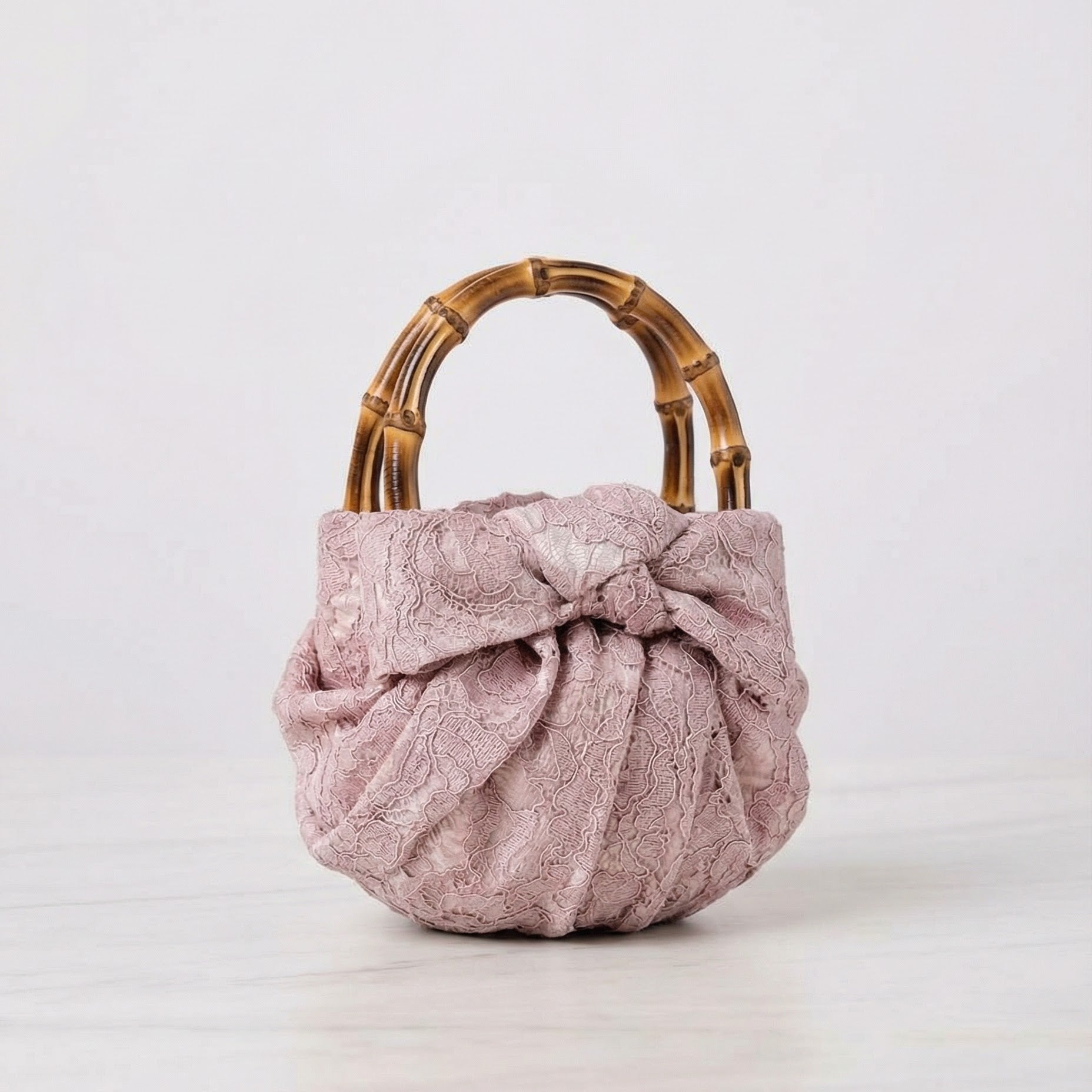 Pink textured ring bag with a bamboo handle on a white background