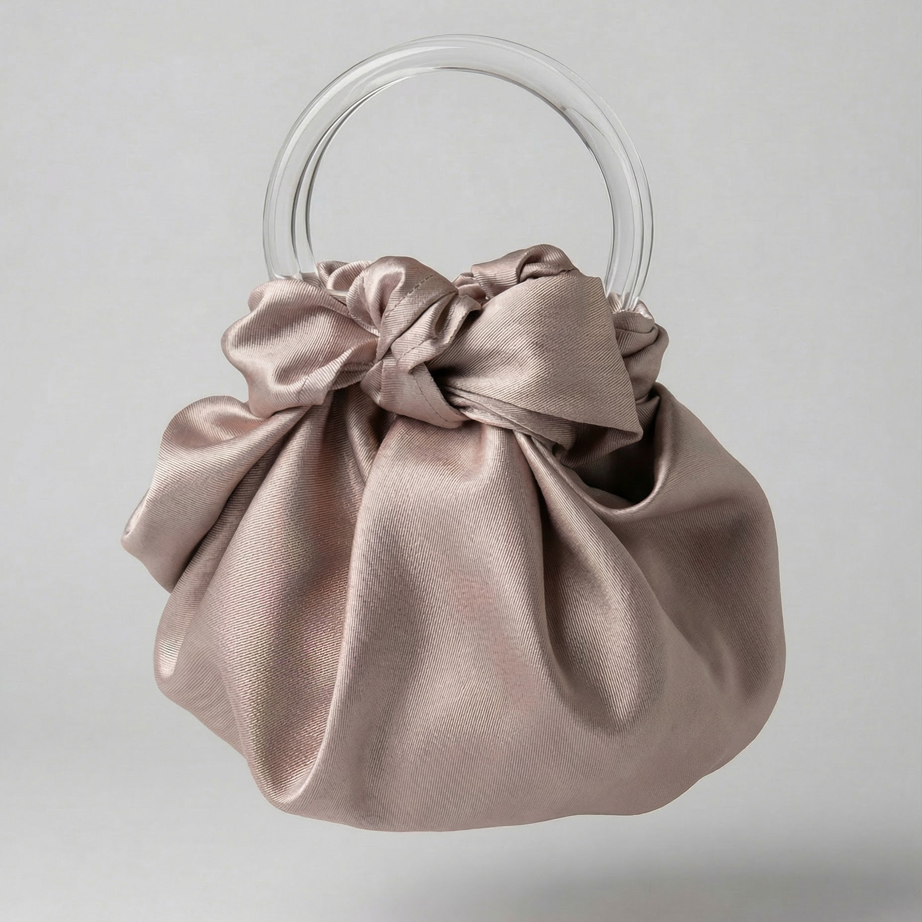 Dusty Rose satin handbag with clear circular handles on a light gray background