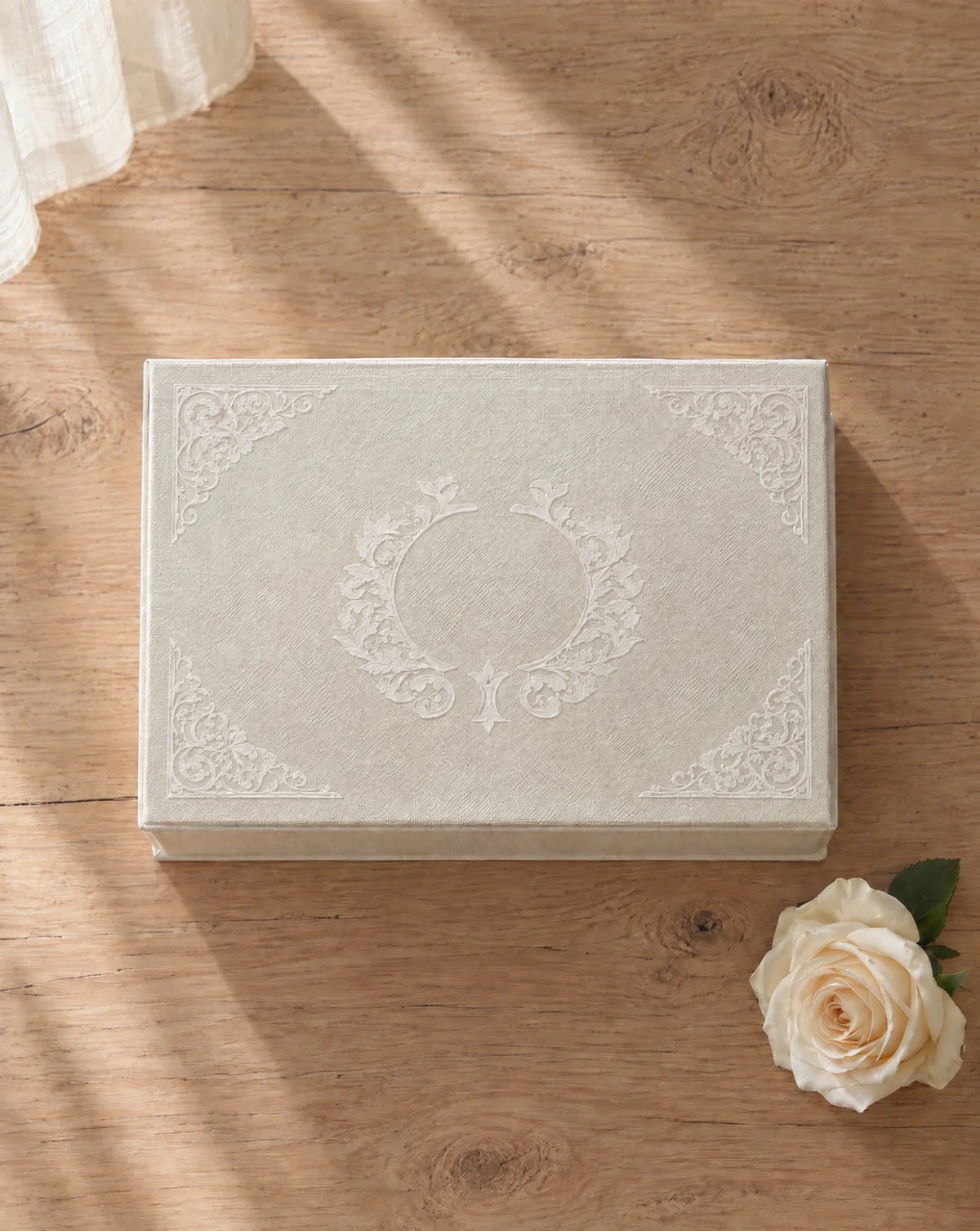 The EVR Box: a linen wedding keepsake box with hanji lace scrollwork on the lid, on a wooden table beside a white rose