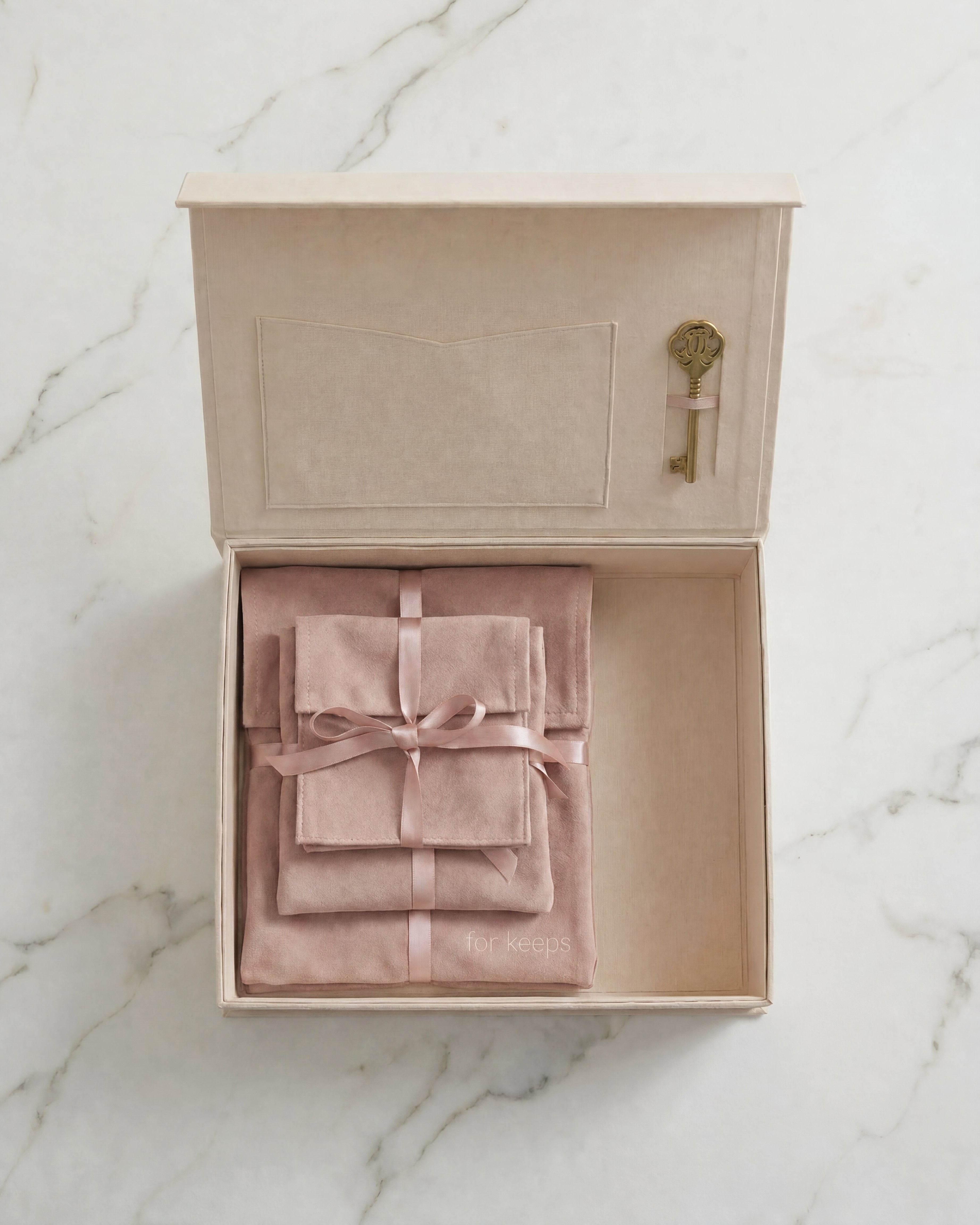 Open linen EVR Keepsake box on marble top with suede keepsake pouches