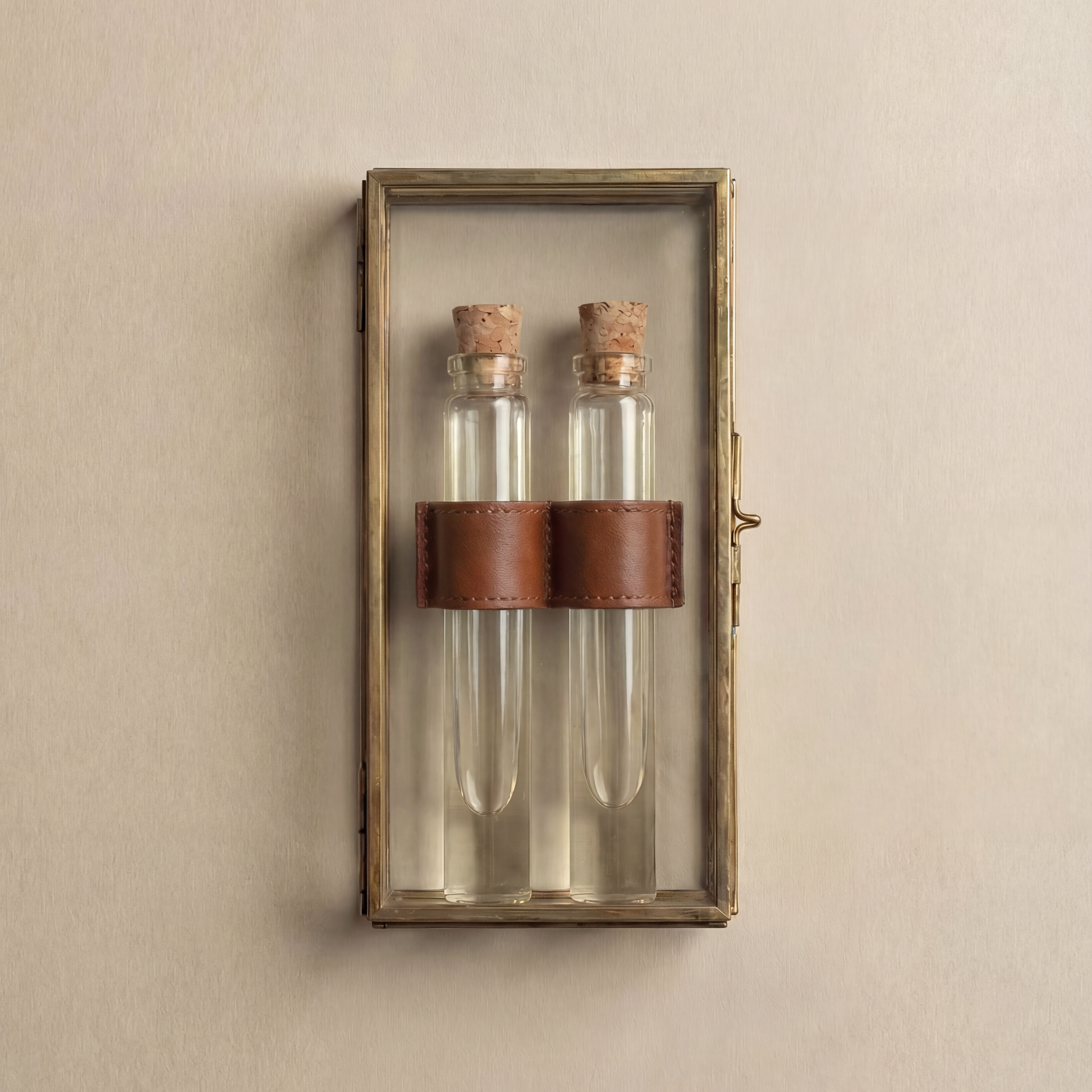 Two perfume vials with cork stoppers wrapped in a leather band inside a glass and brass keepsake box.