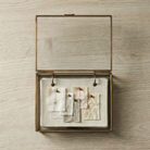 Fabric Swatch booklet set inside a glass and brass keepsake box with fabric samples attached with brass pins. by for keeps.