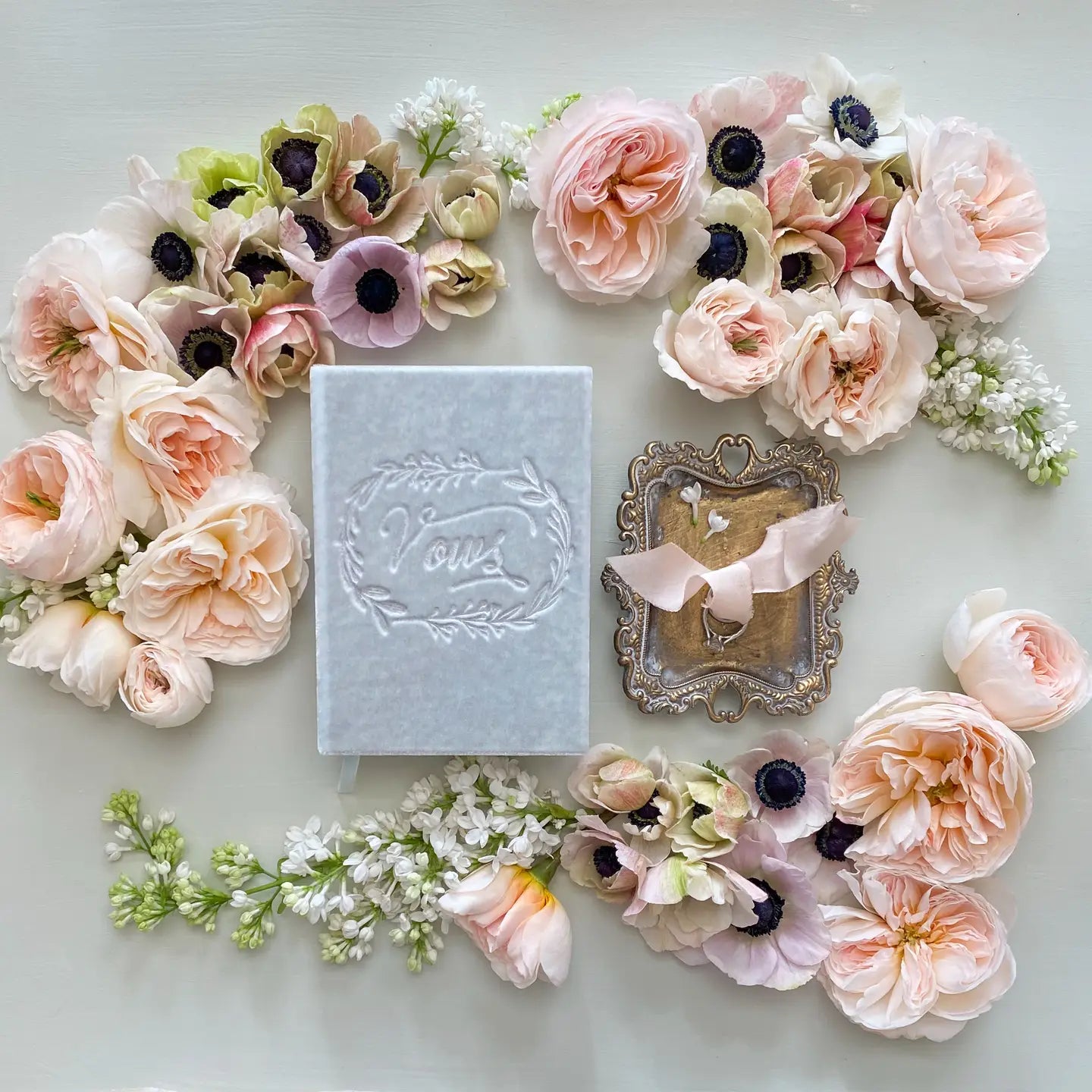 Decorative arrangement of flowers with a small box and mirror on a light background
