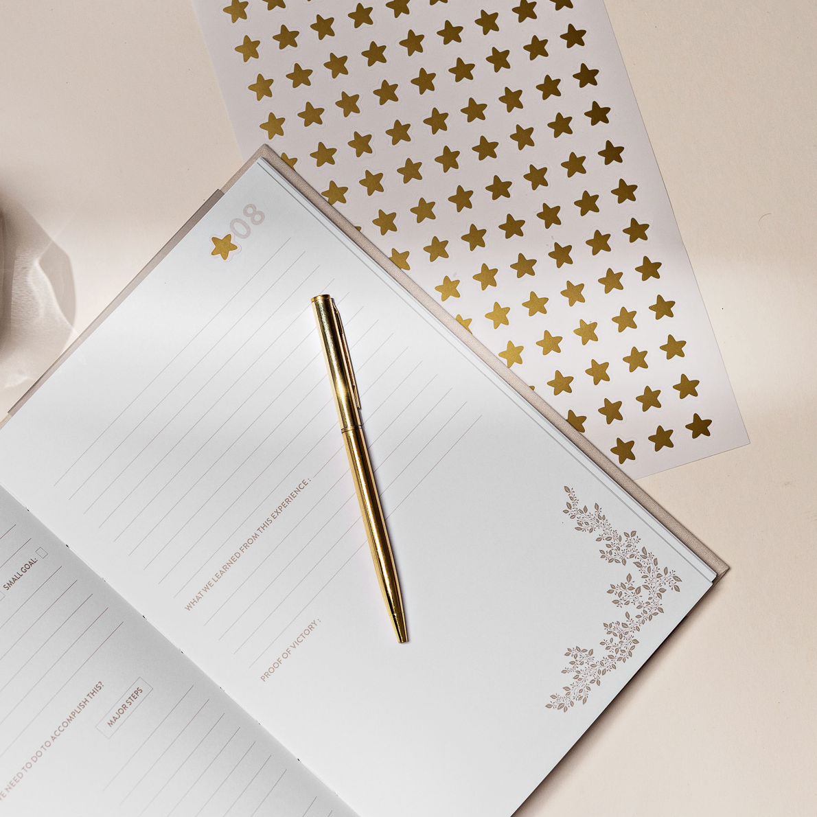 Open journal with a gold pen and star-patterned paper on a light surface