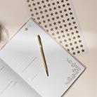 Open journal with a gold pen and star-patterned paper on a light surface