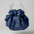 Blue satin handbag with clear circular handles on a light gray background