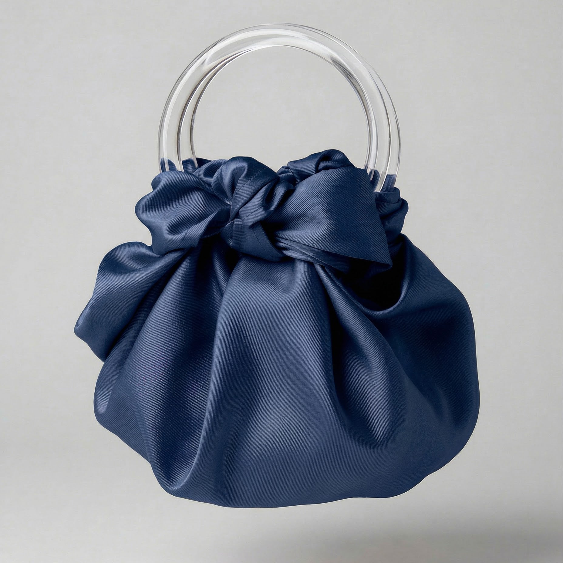Blue satin handbag with clear circular handles on a light gray background