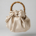 Beige handbag with a bamboo handle on a light gray background