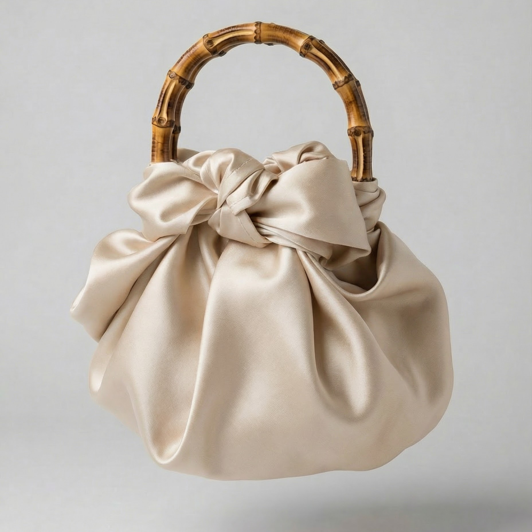 Beige handbag with a bamboo handle on a light gray background