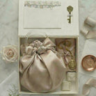 Wedding day and engagement heirloom giift box with a satin bag, locket, ring dish and decorative items on a marble surface