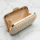Gold clutch with pearl embellishments on a marble surface