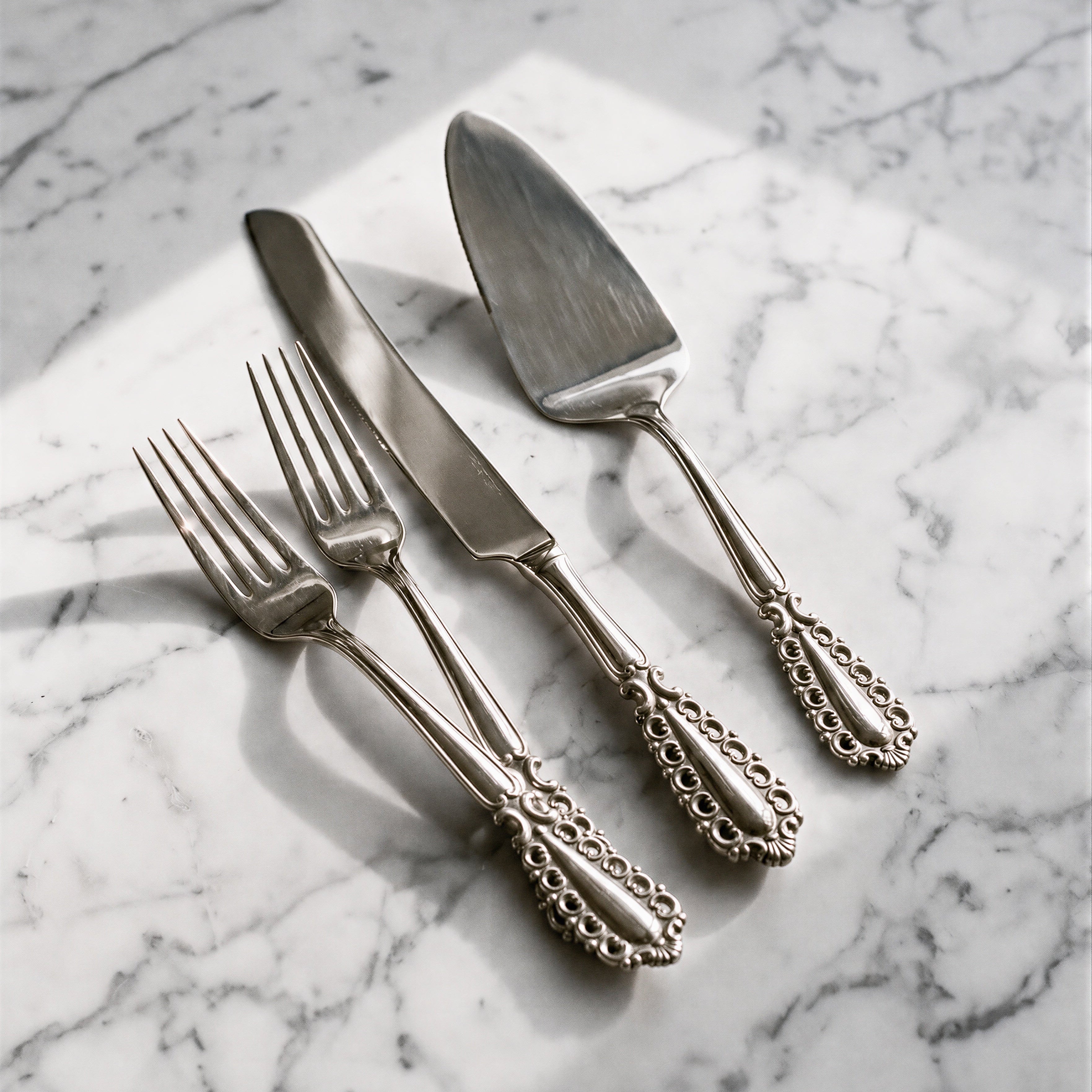 Stainless steel wedding cake knife and server set with two forks on a marble top