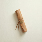 Handmade leather scroll wrapped in suede tie with a stamped brass tag containing the wedding date by For Keeps.