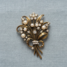 Vintage patina brooch with pearls and diamonds on a light blue textured background