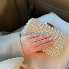Hand holding a pearl embellished clutch in a car.