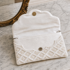 White beaded clutch bag with decorative trim on a marble surface